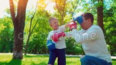 父亲和儿子戴着拳击手套在房子附近的草坪上<strong>打拳</strong>击